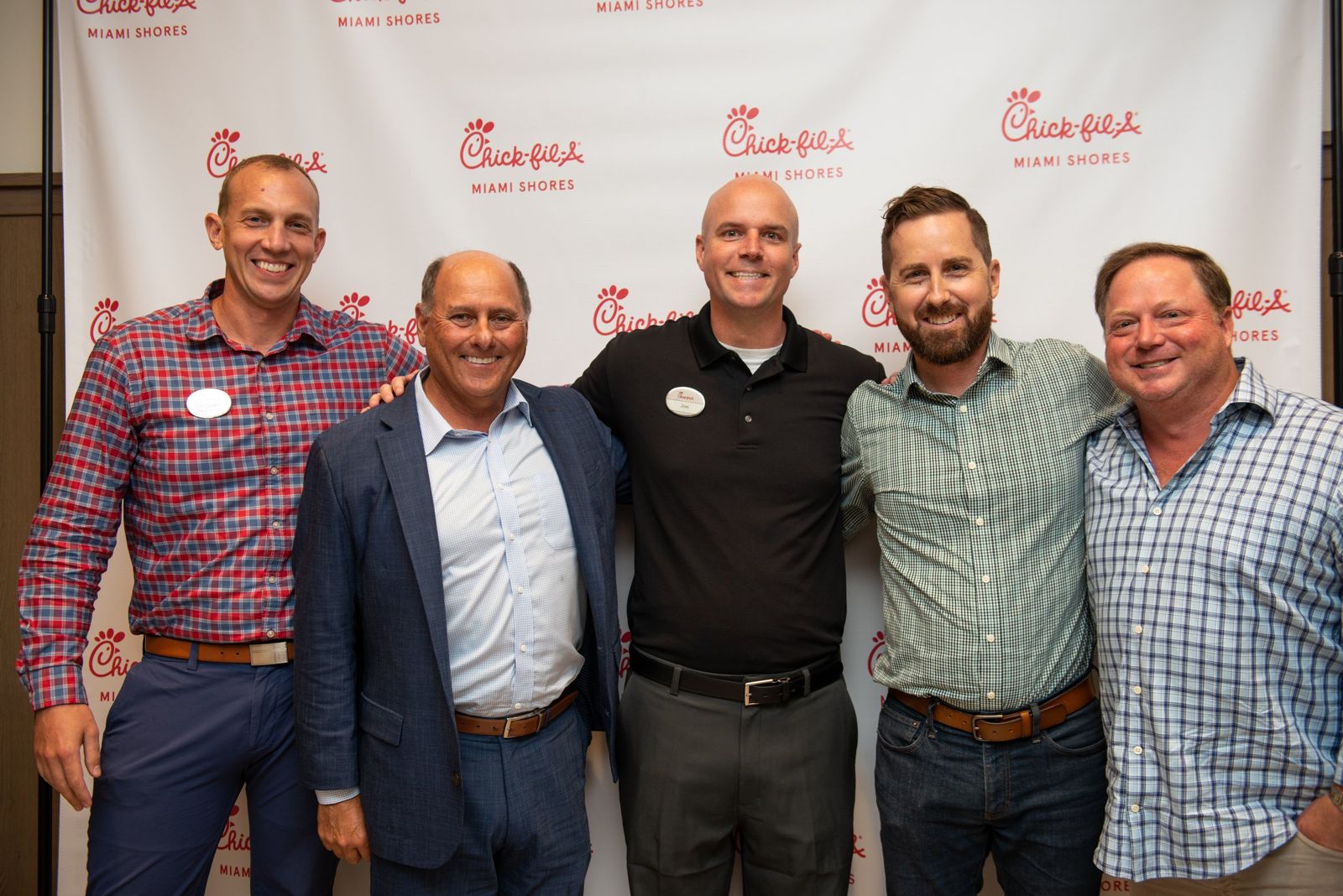 Group of five smiling men in front of a Chick-fil-A Miami Shores backdrop